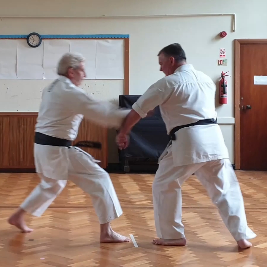 Rear hand pulls Uke's arm while the body shifts and drops